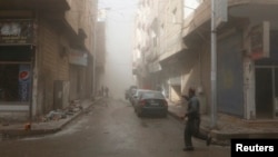 FILE - A man runs while pointing at a site hit by what activists said were airstrikes by forces loyal to Syria's President Bashar al-Assad in Raqqa, eastern Syria, which is controlled by the Islamic State, Nov. 27, 2014. 