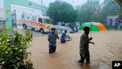 Sejumlah warga berjalan menerjang banjir di luar Rumah Sakit Pemerintah Tambaram di Chennai, India, pada 4 Desember 2023. (Foto: AP)