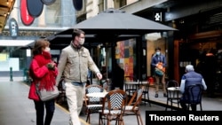 FILE - People walk past a cafe after the coronavirus disease restrictions were eased for the state of Victoria, in Melbourne, Australia, Oct. 28, 2020. 