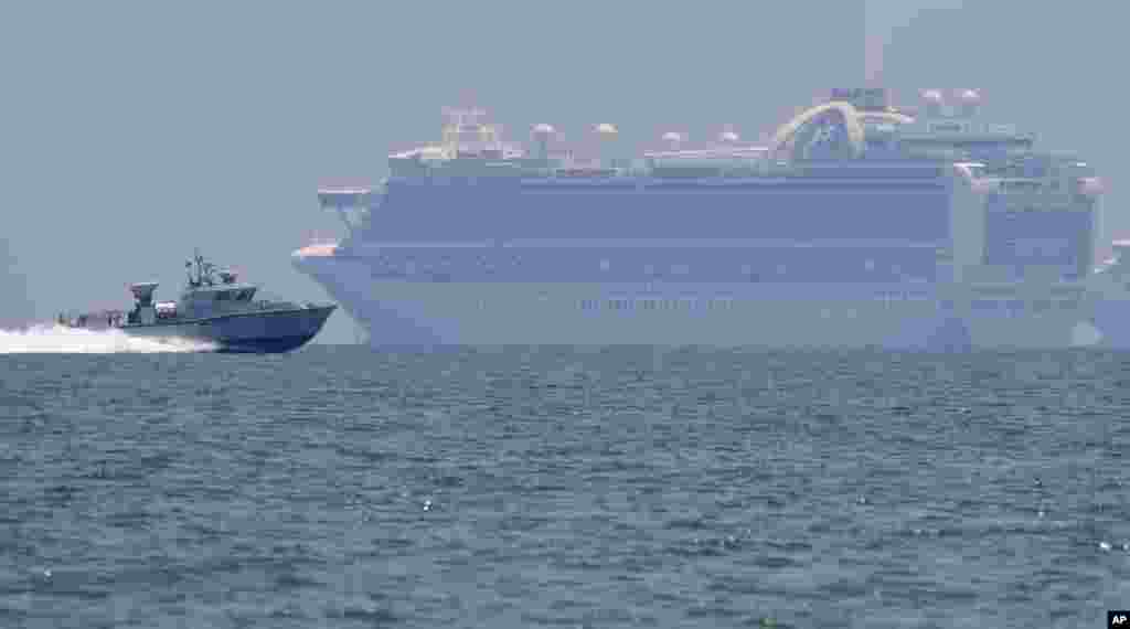 A Philippine military boat passes by the cruise ship Ruby Princess in Manila Bay. The Ruby Princess which is being investigated in Australia for sparking coronavirus infections, has sailed into Philippine waters to bring Filipino crewmen home.