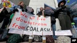 FILE - Demonstrators chant and hold signs behind a display of coal ash and the heavy metals in it during a protest near Duke Energy's headquarters in Charlotte, North Carolina, Feb. 6, 2014.