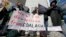 FILE - Demonstrators chant and hold signs behind a display of coal ash and the heavy metals in it during a protest near Duke Energy's headquarters in Charlotte, North Carolina, Feb. 6, 2014.