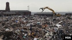 A piece of construction equipment works on the pile of debris, collected during the cleanup from Superstorm Sandy, in the parking lot of Jacob Riis Park in the Rockaway section of the Queens borough of New York, November 14, 2012.