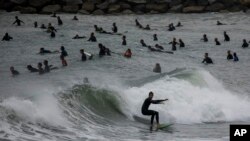 People surf on a beach reopened for sport activities after the coronavirus lockdown in Barcelona, Spain, May 9, 2020.