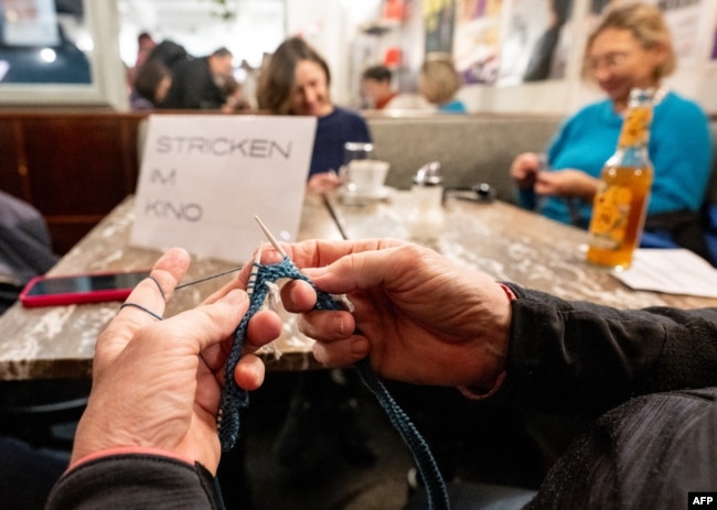 Women knit in the cafeteria prior to the projection of the movie 'The Devil Wears Prada' at the Votive Cinema in Vienna, Austria, on February 16, 2025. (Photo by JOE KLAMAR / AFP)