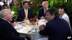 FILE - President Donald Trump, third from right, and first lady Melania Trump, hidden at left, sit down to dinner with Japanese Prime Minister Shinzo Abe, third from left, and his wife Akie Abe, right, at Mar-a-Lago in Palm Beach, Florida, Feb. 10, 2017.