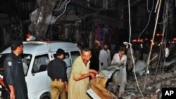 Pakistani people remove debris as they search for blast victims at the site of twin bomb blasts in Peshawar on June 11, 2011.