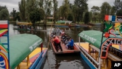 FILE - Amateur soccer players and families travel in a traditional canoe in the Xochimilco borough of Mexico City, on Oct. 20, 2024.