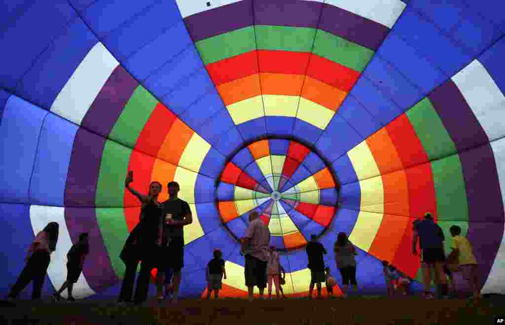 People walk around inside a partially inflated hot air balloon at the 32nd annual OuickChek New Jersey Festival of Ballooning in Readington, New Jersey, USA.