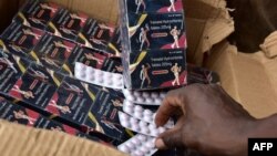 FILE - A policeman shows counterfeit medicine tablets during a police raid against shops selling fake medicine and counterfeit drugs on May 3, 2017 at the Adjame market in Abidjan. 