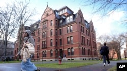 FILE - People walk between buildings, Dec. 17, 2024, on the campus of Harvard University in Cambridge, Mass.