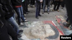 Demonstranti gaze po slici predsednika Bašara al-Asada, tokom protesta protiv njegovg režima u Alepu, 4. januara 2013.