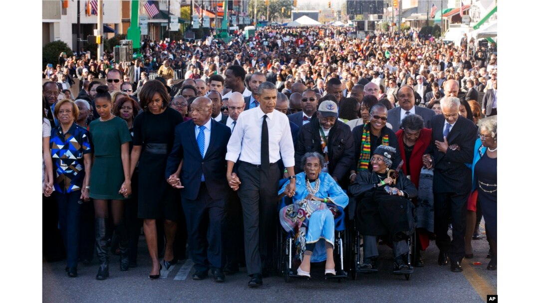 El presidente Barack Obama camina de la mano a Amelia Boynton Robinson a través del puente Edmund Pettus en Selma, Alabama, 7 de marzo de 2015, en el 50 aniversario del histórico día del movimiento de derechos civiles, que en 1965 realizó marchas de Selma a Montgomery, Alabama.