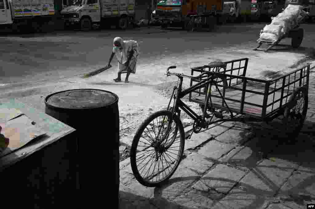 A woman collects slaked lime from the ground at a wholesale market during a 15-day lockdown announced by West Bengal&#39;s government to curb the spread of the COVID-19 disease, in Kolkata, India.