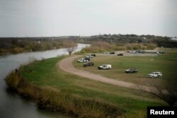 FILE - U.S. border patrol cars are seen through the fence of the bridge connecting Eagle Pass, Texas, with Piedras Negras, Mexico, near the banks of Rio Bravo, from Piedras Negras, Mexico, Feb. 7, 2019.