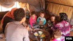 Members of an internally displaced family are sharing a meal in a tent in Idlib, Syria, July 24, 2020. Most people in the region rely on humanitarian aid just to stay alive.