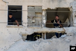 Municipality workers survey the damage to an apartment building struck by a rocket fired from Lebanon in Kiryat Ata, northern Israel, Oct. 19, 2024.