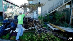 Caleb Cormier moves debris after Hurricane Delta moved through, Oct. 10, 2020, in Lake Charles, La. Delta hit as a Category 2 hurricane with top winds of 100 mph (155 kph) before rapidly weakening over land. 