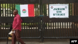 A gateman carries a chair beside the banner of the National Labour Congress at the gate of the Federal High Court of Nigeria after the Nigerian unions began an indefinite strike in Abuja, on June 3, 2024.