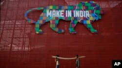 ভারতের মুম্বাইতে মেক ইন ইন্ডিয়া শীর্ষ সম্মেলনের প্রস্তুতির জন্য শ্রমিকরা কাঠের স্তূপ বহন করছে। (ফাইল ছবি) ৯ ফেব্রুয়ারী, ২০১৬। 