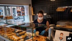 Una mujer prepara sandwiches en Barcelona, pero usando mascarilla. El gobierno español ha anunciado un estado de emergencia de dos semanas durante el cual intentarán contener el brote.