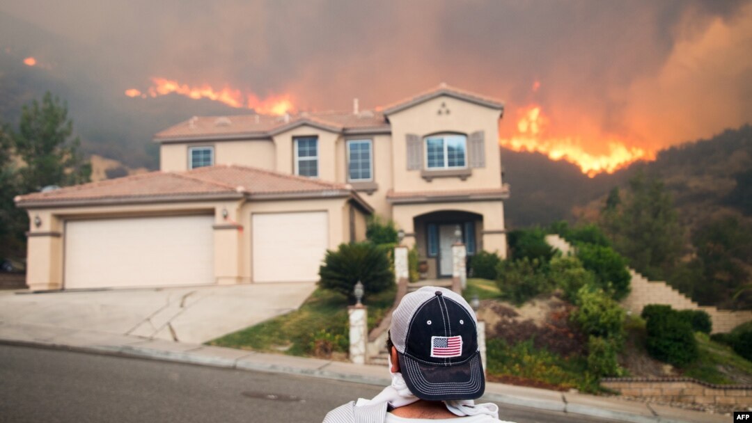 Seorang pria mengamati kebakaran hutan yang berkobar mendekati rumahnya di Lake Elsinore, California, Kamis (9/8). Kebakaran hutan ini telah menjadi kebakaran terbesar dalam sejarah California.