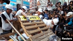 Para pekerja menghancurkan barikade di sebuah perempatan di jalan utama pusat belanja Mongkok, Hong Kong (25/11). 