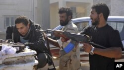 Libyan revolutionary fighters detain a suspected loyalist, left, in downtown Sirte, Libya, Wednesday, Oct. 12, 2011.