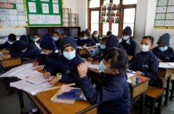 FILE - Children wearing facial masks, as a precaution after Nepal confirmed the first case of coronavirus in the country, attend a lecture at Matribhumi School in Thimi, Bhaktapur, Nepal, Jan. 29, 2020.