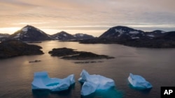 FILE - Large icebergs float away as the sun rises near Kulusuk, Greenland, on Aug. 16, 2019. 