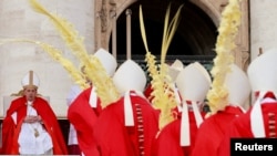Miembros del clero sostienen palmas mientras el papa Francisco preside la misa del Domingo de Ramos en la Plaza de San Pedro en el Vaticano, el 24 de marzo de 2024.