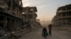 FILE - Haider, left, and Abdullah carry belongings they collected from their damaged house to wash before returning to live in the Old City of Mosul, Iraq, Nov. 15, 2017. 