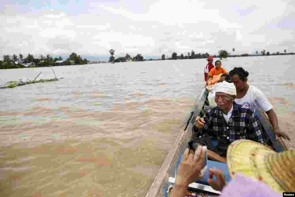 People row their canoes on a flooded street at a village in Kawlin township, Sagaing division