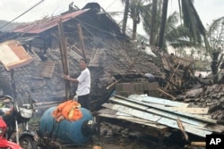 Seorang warga berdiri di samping rumah yang rusak akibat Topan Man-yi di Viga, Provinsi Catanduanes, timur laut Filipina, Minggu, 17 November 2024. (MDRRMO Viga Catanduanes via AP)