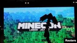 FILE - A fan of video game Minecraft waves a foam pick-axe in front of a screen display at the Minecon convention in London, July 4, 2015. 