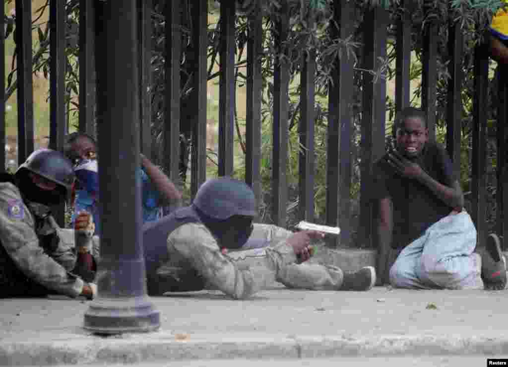 A boy reacts as a man in a Haitian National Police uniform aims a gun during a shooting in Champ de Mars, Port-au-Prince, Feb. 23, 2020.