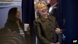 Democratic presidential candidate Hillary Clinton laughs with Senior Policy Advisor Maya Harris, left, and other staff members aboard her campaign plane in White Plains, N.Y., Oct. 2, 2016.