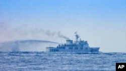 资料照片：一艘中国海警船在南海争议海域的第二托马斯浅滩(仁爱礁)附近，靠近长期搁浅的菲律宾军舰“马德雷山”号(BRP Sierra Madre)，进行了一次看似高压水炮演练的行动。(2025年8月20日)