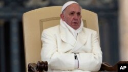 El papa Francisco intenta mantenerse caliente durante una audiencia general en la plaza de San Pedro.