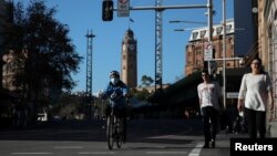 Seorang kurir dan para pejalan kaki di pusat kota menyusul pelonggaran sejumlah pembatasan terkait pandemi virus corona (Covid-19) di Sydney, Australia, Juni 2020. 