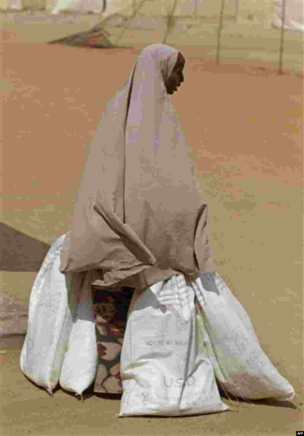 A woman holds partially filled aid bags after waiting in a queue for food aid at the border town of Dadaab, Kenya, Saturday, July 23, 2011. People who can barely stay on their feet due to hunger walk for days or even weeks through parched wasteland to f