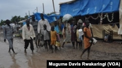 People walk along dirt roads that have been turned into streams of mud by the rains, in the UNMISS base in Malakal, South Sudan, where 19,000 people have sought shelter from months of fighting.