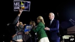 A protester is held back by Biden's adviser Symone Sanders, wearing stripes, and his wife Jill, 2nd right, as former Vice President Joe Biden stands (R) during a primary election night rally in Los Angeles, March 3, 2020.