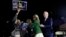 A protester is held back by Biden's adviser Symone Sanders, wearing stripes, and his wife Jill, 2nd right, as former Vice President Joe Biden stands (R) during a primary election night rally in Los Angeles, March 3, 2020.