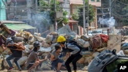 Armed riot policemen charge after firing teargas a rubber bullets as anti-coup protesters abandon their makeshift barricades and run in Yangon, Myanmar, March 16, 2021.