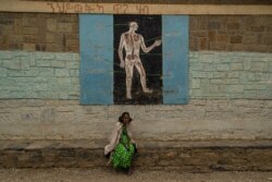 A woman sits in front during a science lesson painted on a wall of one school now housing displaced families, in Mekelle, Ethiopia, June 3, 2021. (Yan Boechat/VOA)
