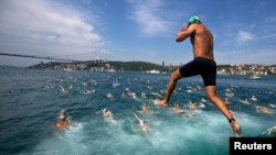 A competitor jumps into the water to swim from Asia to Europe during the annual Bosphorus Cross-Continental swimming competition in Istanbul ,July 7, 2013. 