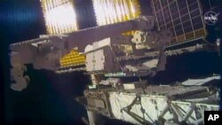 En esta foto distribuida por la NASA, los astronautas Chris Cassidy y Bob Behnken reemplazan baterías de la Estación Espacial Internacional el 26 de junio de 2020.
