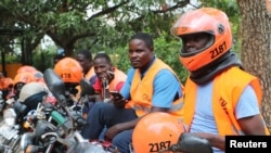 FILE - Motorcycle taxi drivers known as boda bodas, wear SafeBoda safety gear as they wait for customers along a street in Kampala, Uganda, Oct. 5, 2018.