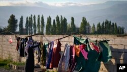 Seorang pengungsi asal Suriah tampak menjemur pakaian keluarganya di luar tenda di kamp pengungsi di Bar Elias, Lembah Bekaa, Lebanon, pada 7 Juli 2022. (Foto: AP/Bilal Hussein)